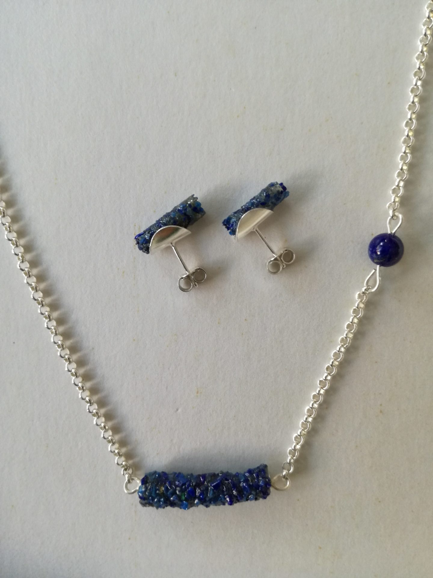 Zilveren ketting met lapis lazuli kraal en koker gecombineerd met lapis lazuli oorstekers tevens uitgevoerd in zilver.